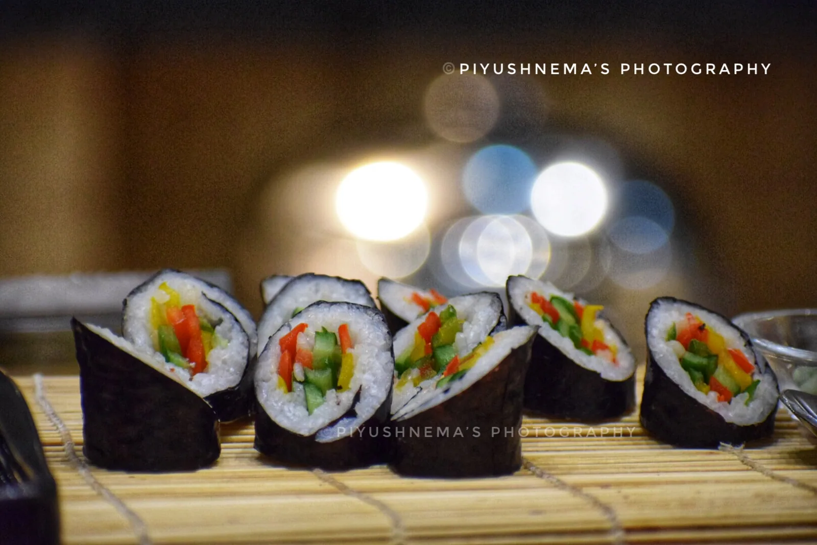 Maki rolls under warm bokeh — photography by Nemora